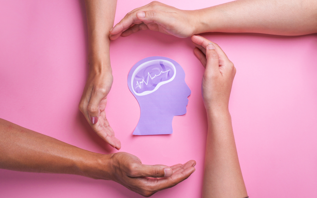 Manos rodeando la silueta de una cabeza con un cerebro ilustrado, simbolizando cuidado y apoyo a la salud mental.